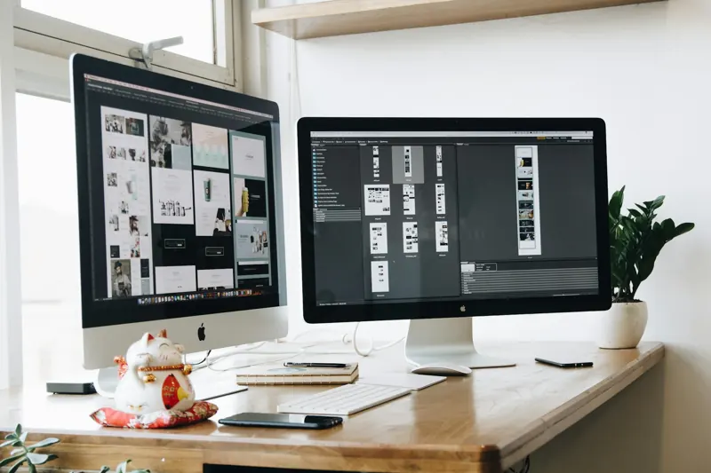 Bureau met twee schermen vol ontwerpwerk
